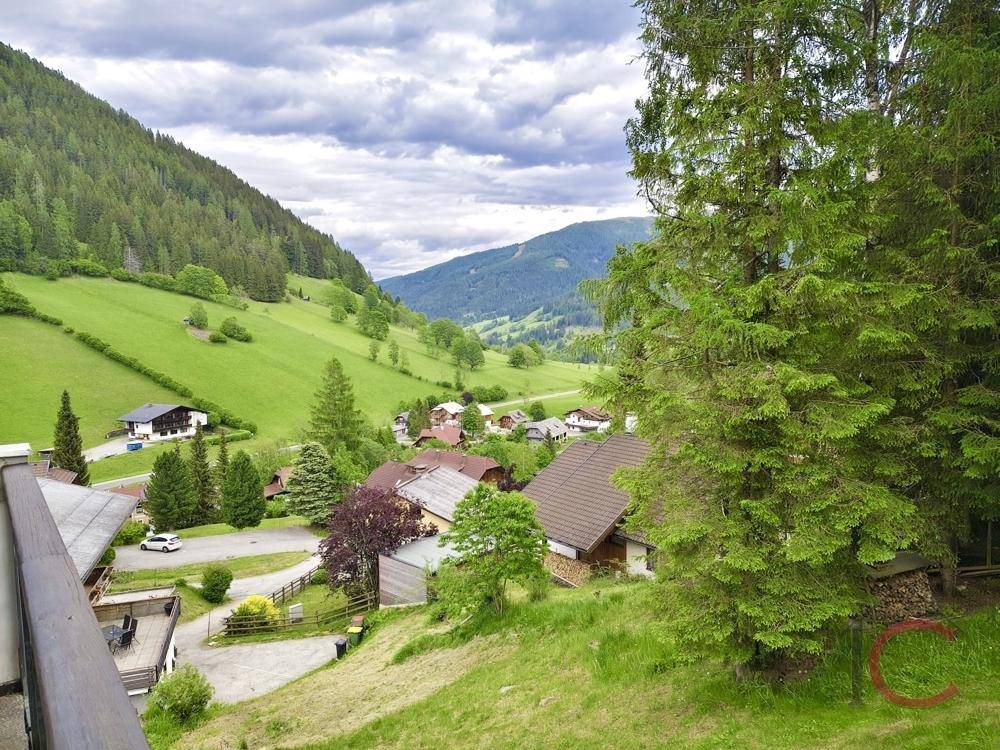 Panoramablick auf ein malerisches Tal mit grünen Hügeln und traditionellen Häusern.