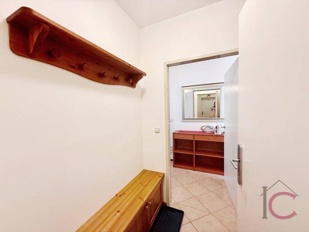 Eingangsbereich mit Holzbank, Garderobe und Zugang zu weiteren Räumen.