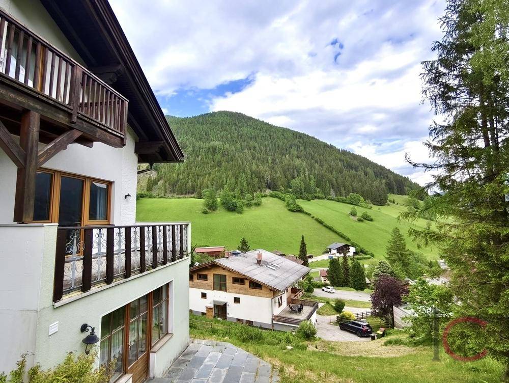 Traditionelles Gebäude mit Balkonen und Blick auf die grüne Berglandschaft.