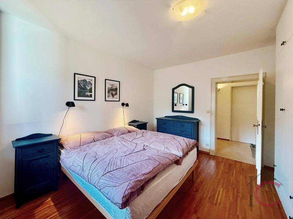 Schlafzimmer mit Doppelbett, Nachttischen und Kommode, mit Holzboden und weiß gestrichenen Wänden.