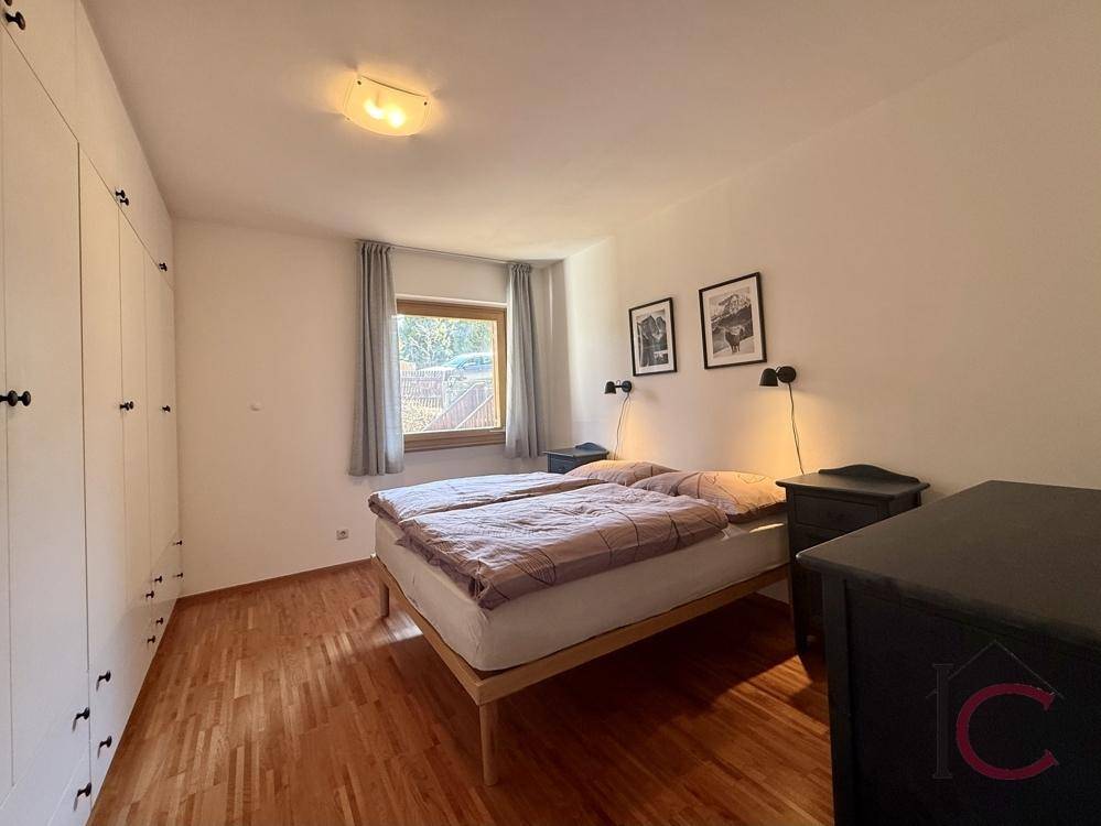 Schlafzimmer mit Doppelbett, großem Kleiderschrank und Holzboden, hell und funktional.