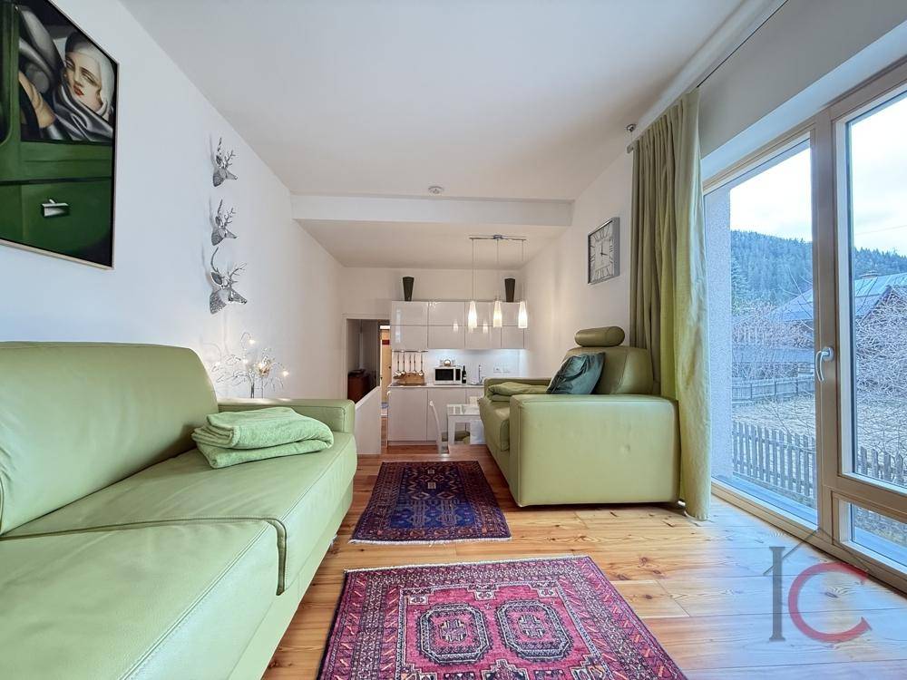 Helles Wohnzimmer mit bequemen Sofas, Holzboden und Blick auf die grüne Umgebung.