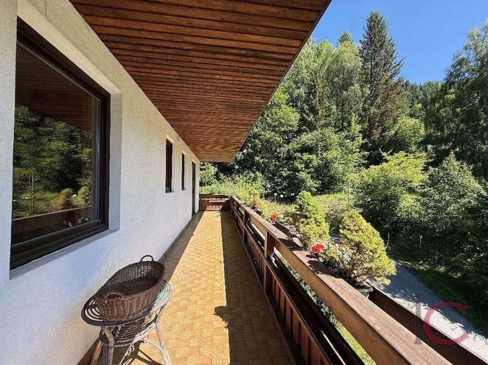 Langer Balkon mit Fliesenboden und Blick auf die umliegende Waldlandschaft.