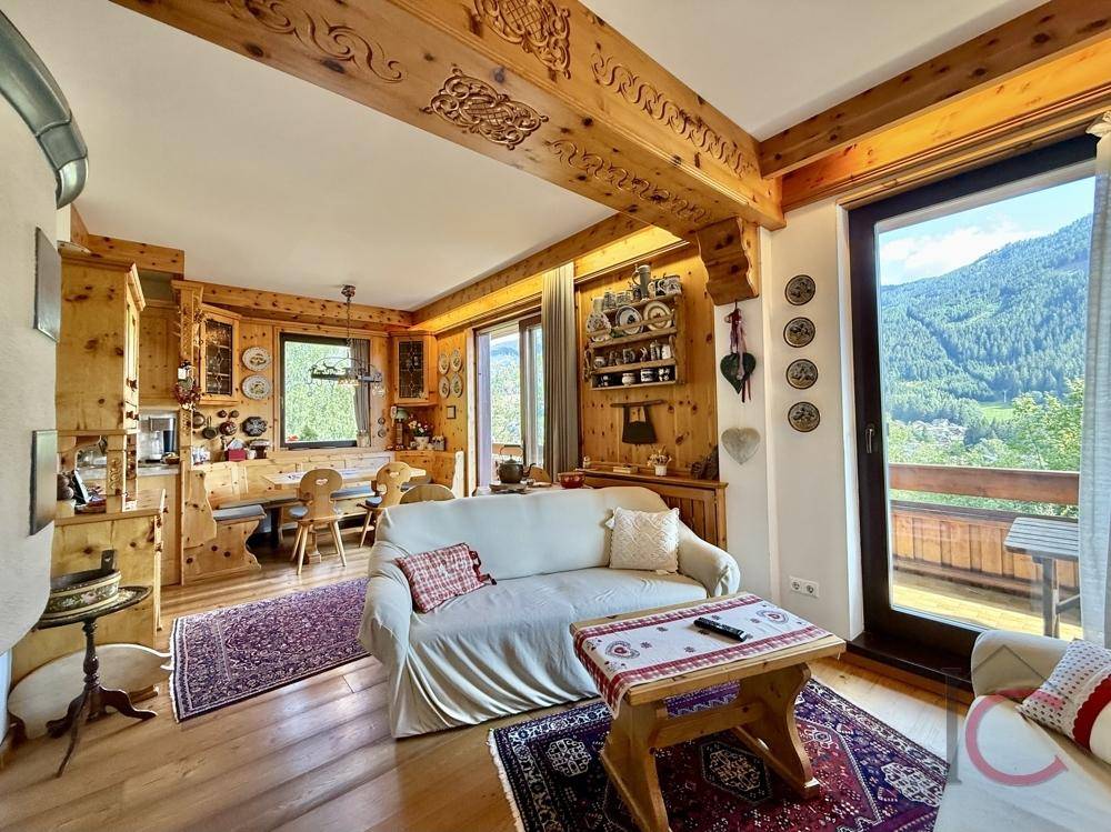Offener Wohn- und Essbereich im alpinen Stil mit Holzbalken und Bergblick.