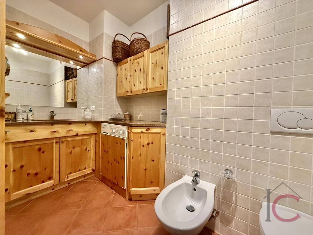 Badezimmer mit Bidet, Holzwaschtisch und hellen Fliesen im traditionellen Stil.