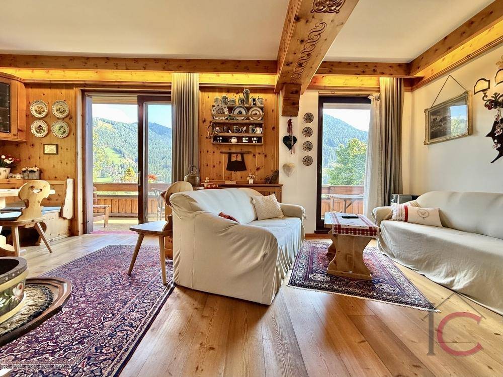 Heller Wohnbereich mit Holzbalken, Parkettboden und Zugang zum Balkon mit Bergblick.