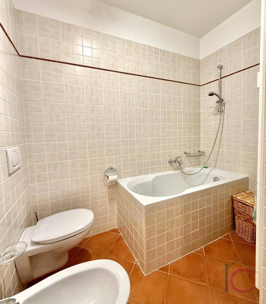 Badezimmer mit Badewanne, Toilette und hellen Fliesen im traditionellen Design.