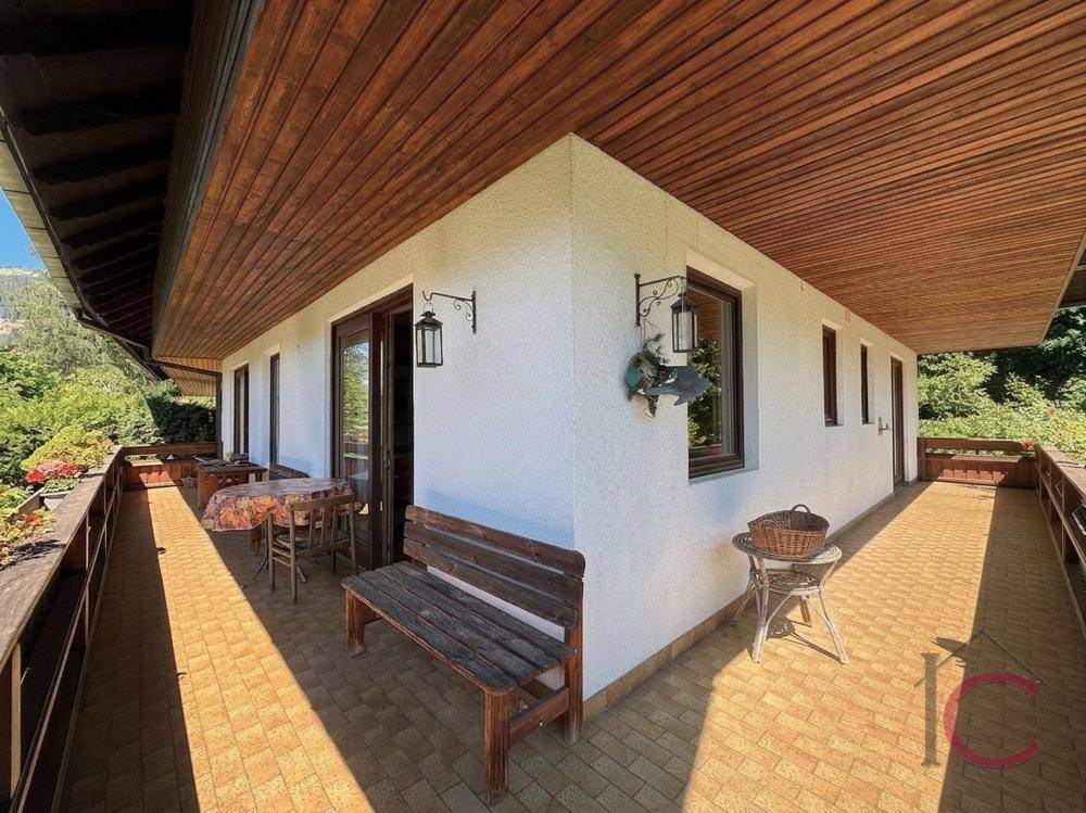 Breiter Balkon mit Fliesenboden und Holzbänken, ideal für entspannte Stunden im Freien.
