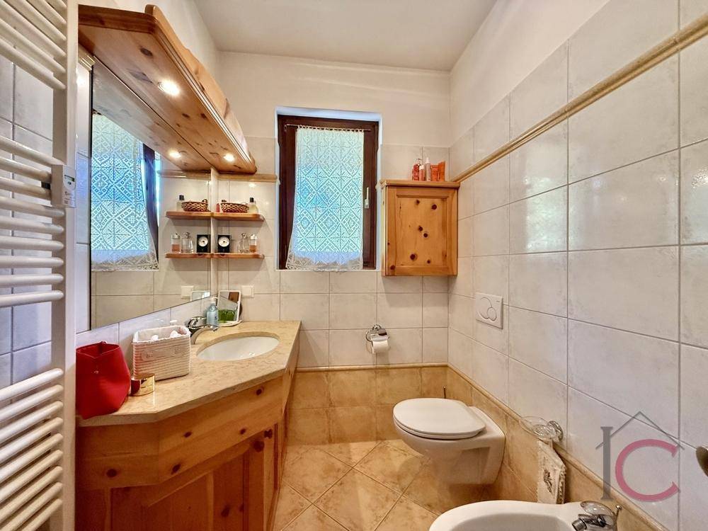 Badezimmer mit Fenster, Waschtisch aus Holz und beheiztem Handtuchhalter.
