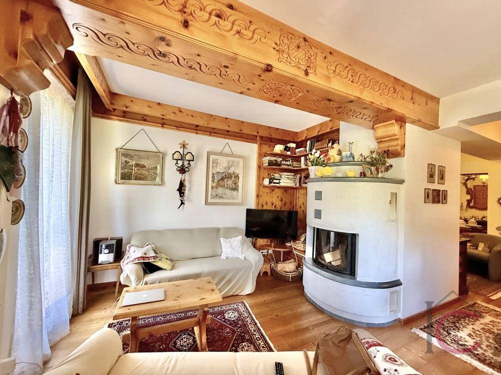 Gemütliches Wohnzimmer mit Kamin, Holzbalken und traditioneller Einrichtung im alpinen Stil.