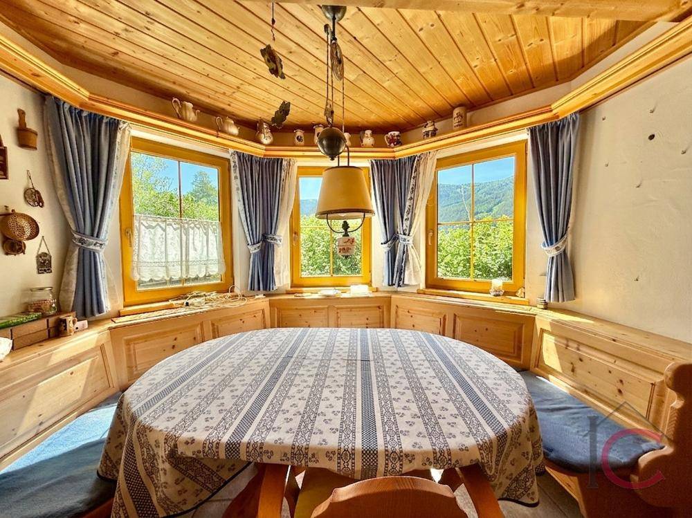Heller Essbereich mit Holztisch, Eckbank und großen Fenstern mit Bergblick.