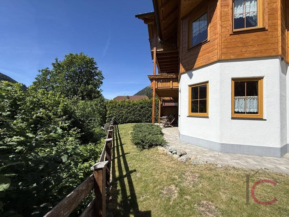 Seitenansicht des traditionellen Hauses mit Holzbalkonen und einem grünen Gartenbereich.