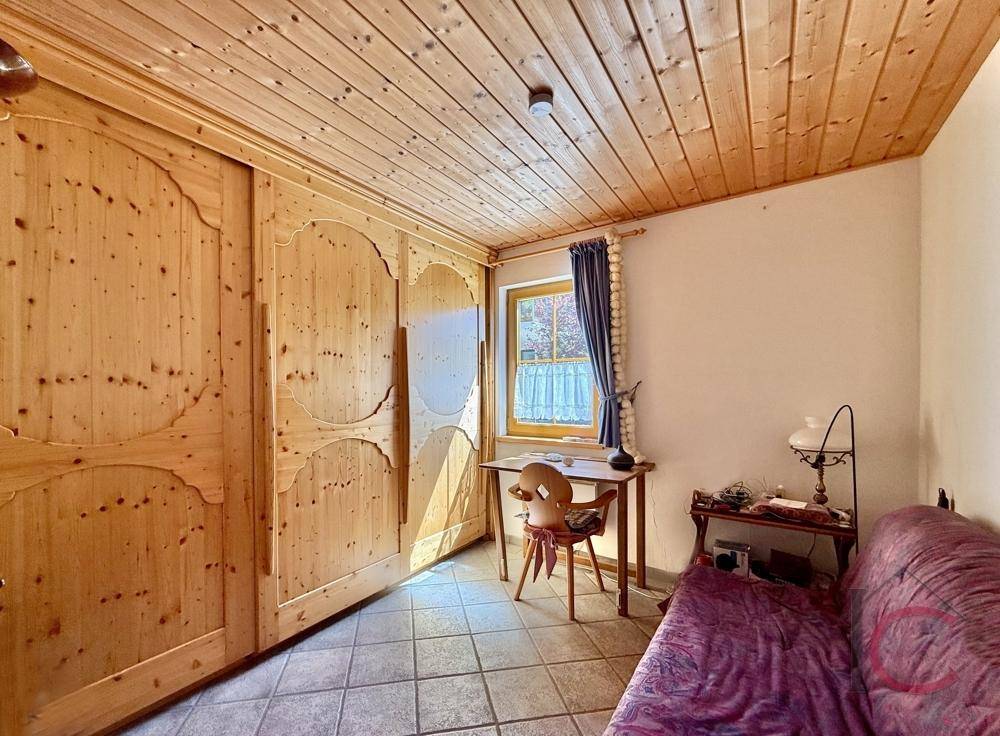 Helles Schlafzimmer mit Holzboden, Schreibtisch und großem Einbauschrank.