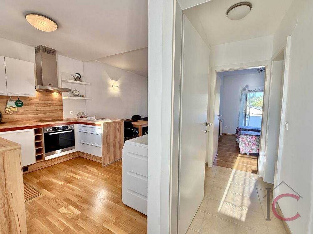 Heller Flur mit Fliesenboden, der zu einem Schlafzimmer und einer offenen Küche führt.