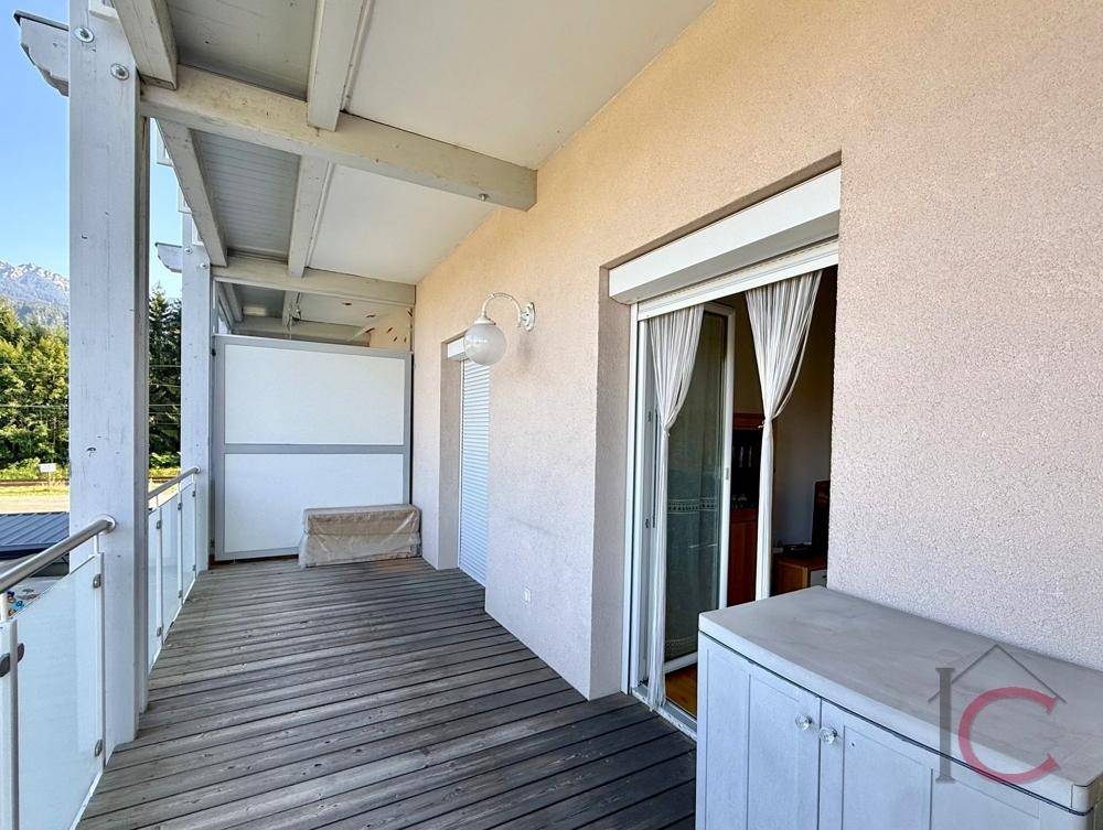 Geräumiger Balkon mit Holzboden und Bergblick, ideal für Entspannung im Freien.