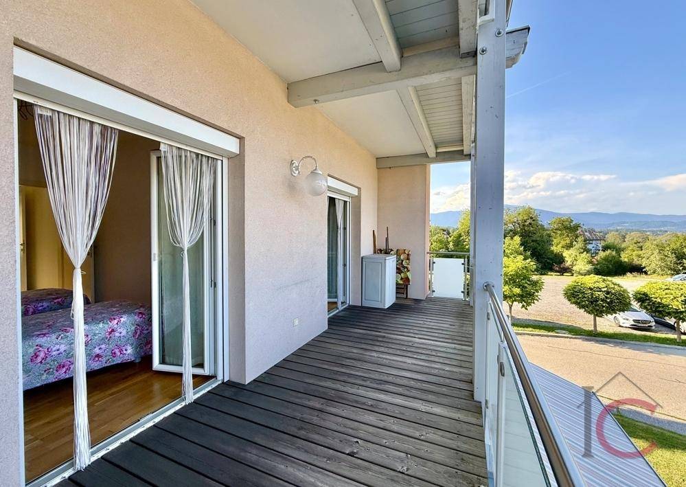 Großer Balkon mit Holzboden und Zugang zu einem Schlafzimmer, bietet einen weiten Ausblick.