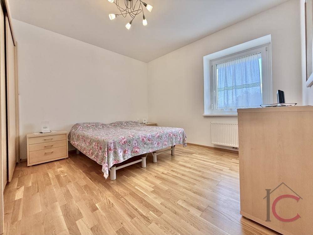 Helles Schlafzimmer mit Doppelbett, Holzboden und großem Fenster für viel Tageslicht.