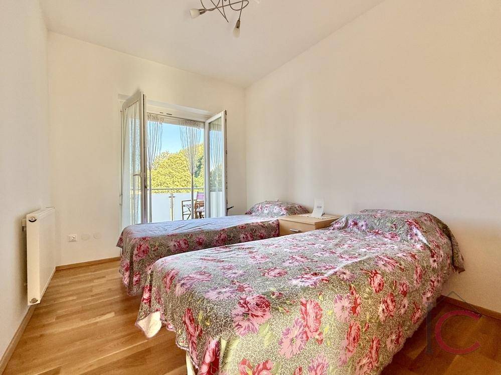 Helles Schlafzimmer mit zwei Einzelbetten, Holzboden und direktem Balkonzugang.