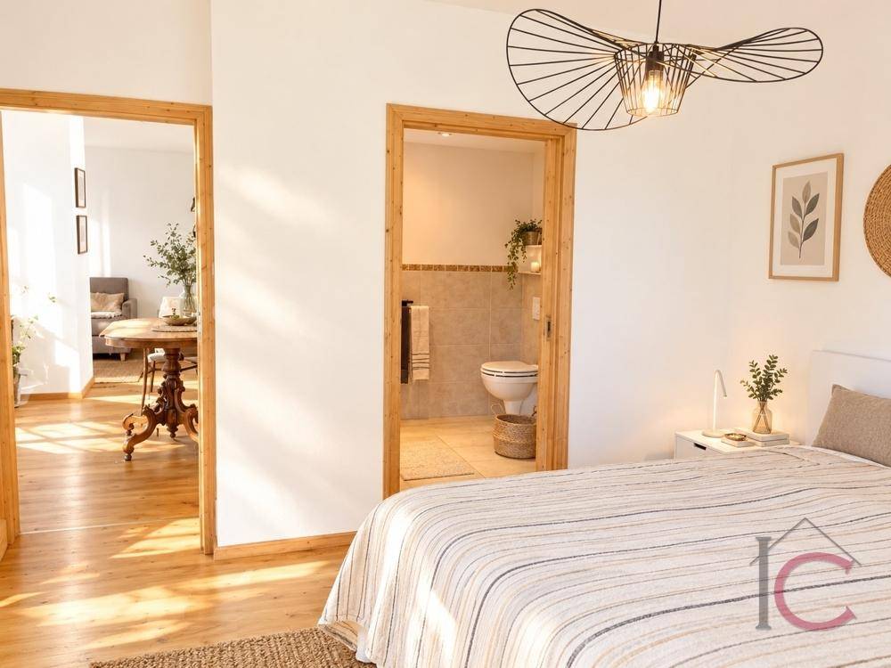 Schlafzimmer mit Holzboden und Zugang zu einem Badezimmer sowie einem weiteren Raum.