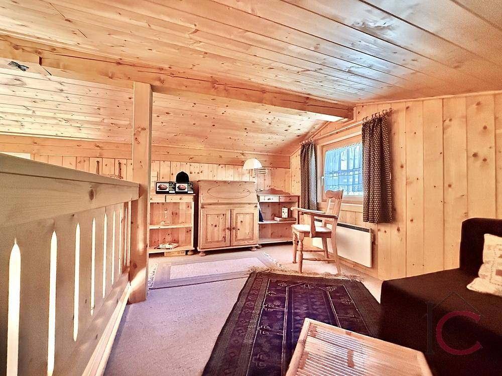 Gemütlicher Galeriebereich mit Holzboden, Sitzgelegenheit und Dachschräge.
