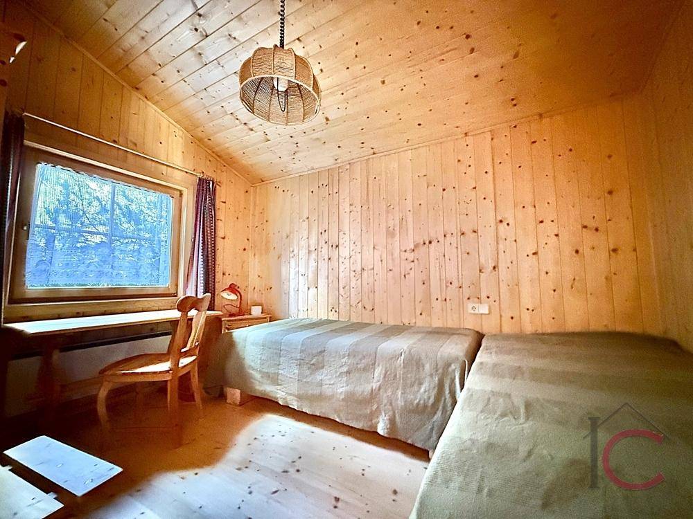 Helles Schlafzimmer mit zwei Einzelbetten, Holzvertäfelung und Blick ins Grüne.