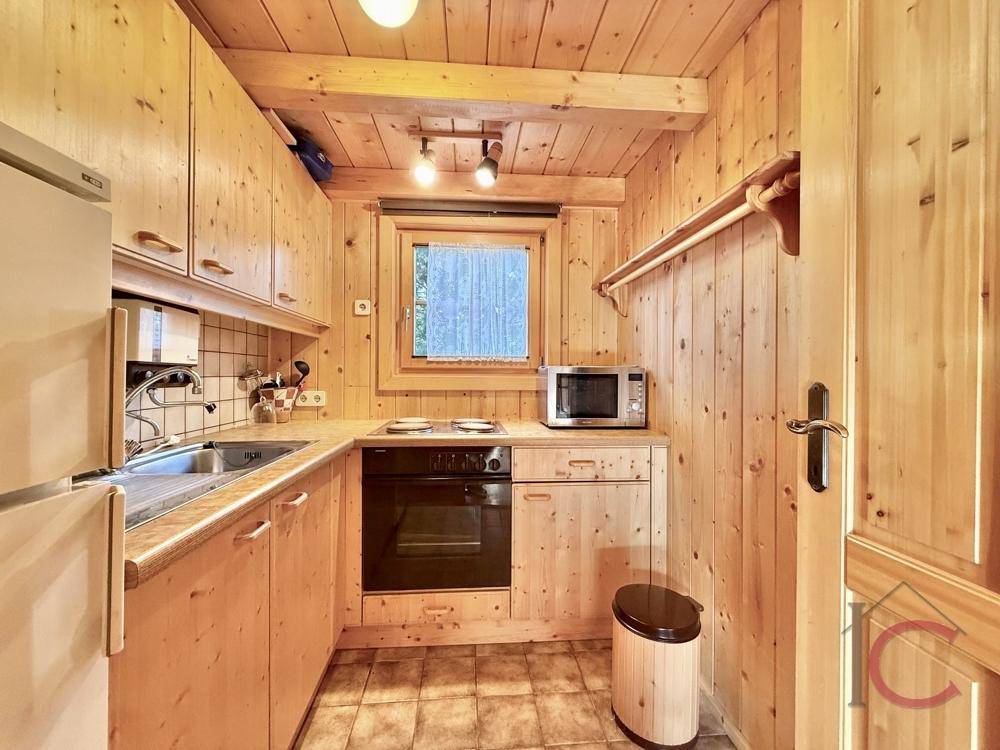 Funktionale Küche mit Holzschränken, Einbaugeräten und Fenster zur Natur.