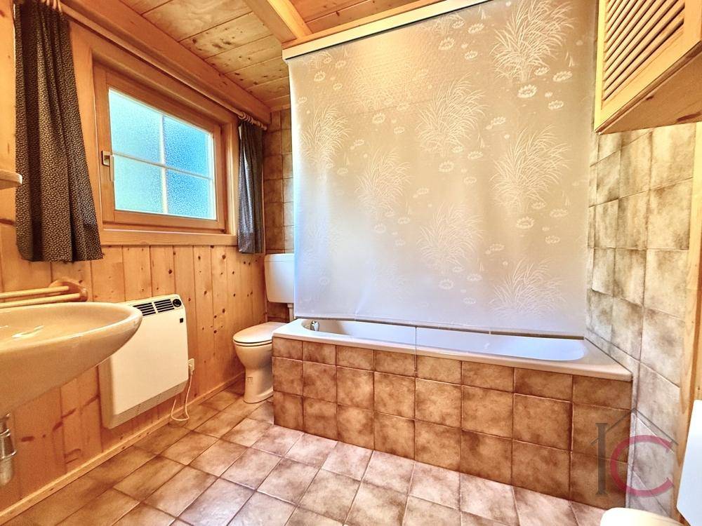 Traditionelles Badezimmer mit Badewanne, Waschbecken und braunen Fliesen.