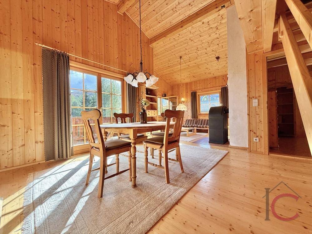 Heller Essbereich mit Holztisch, Holzstühlen und Blick auf die umliegende Natur.