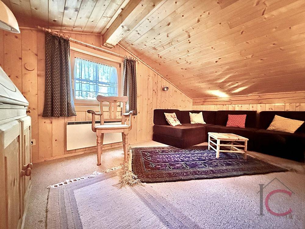 Heller Galeriebereich mit Teppichboden, Sofa und Fenster in der Dachschräge.
