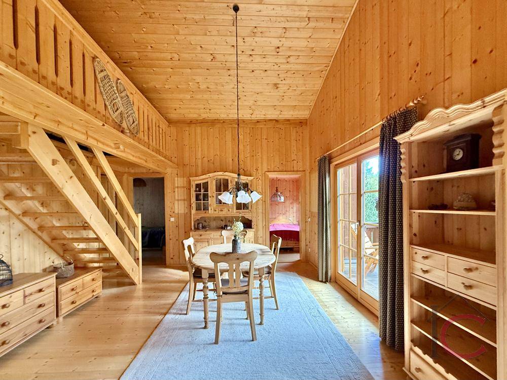 Geräumiger Essbereich mit Holzmöbeln, Treppe zum Obergeschoss und Zugang zum Balkon.