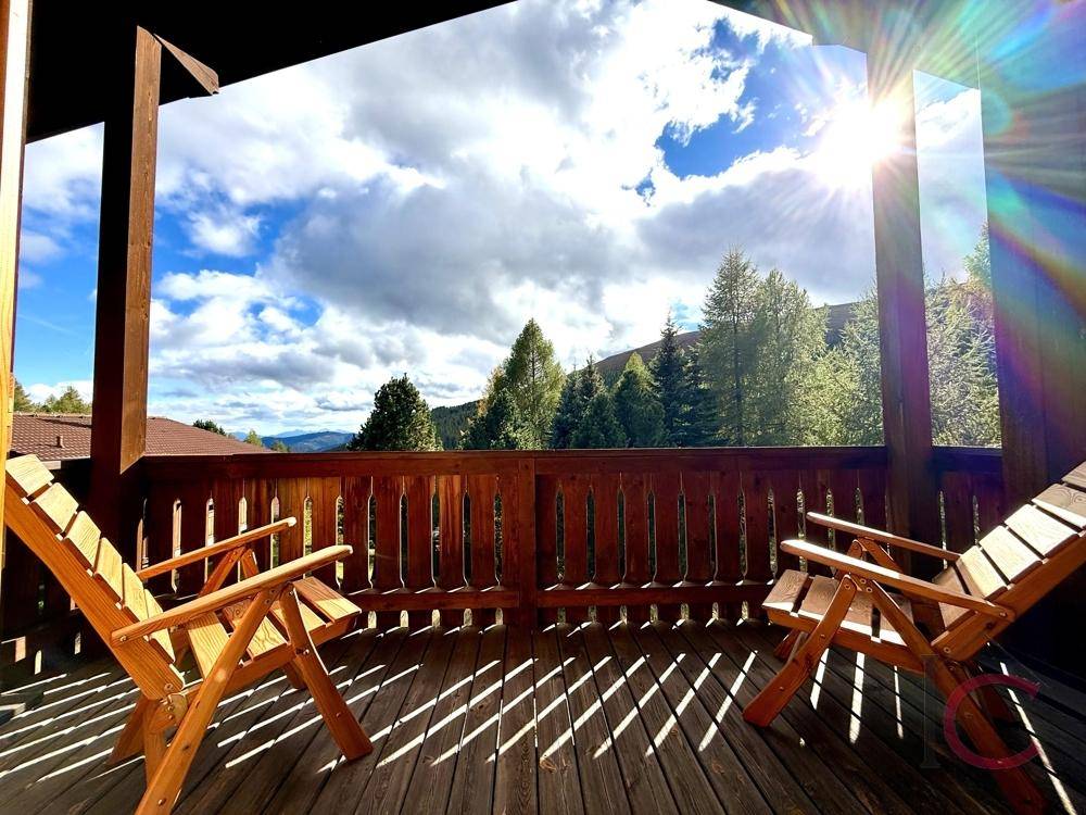 Sonniger Holzbalkon mit Liegestühlen und weitem Blick auf die Berglandschaft.