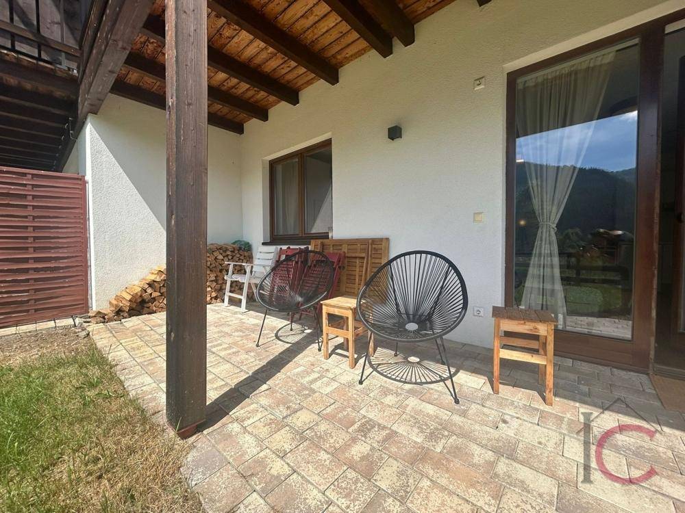 Überdachte Terrasse mit Sitzgelegenheiten und Holzstapel, ideal für entspannte Stunden im Freien.