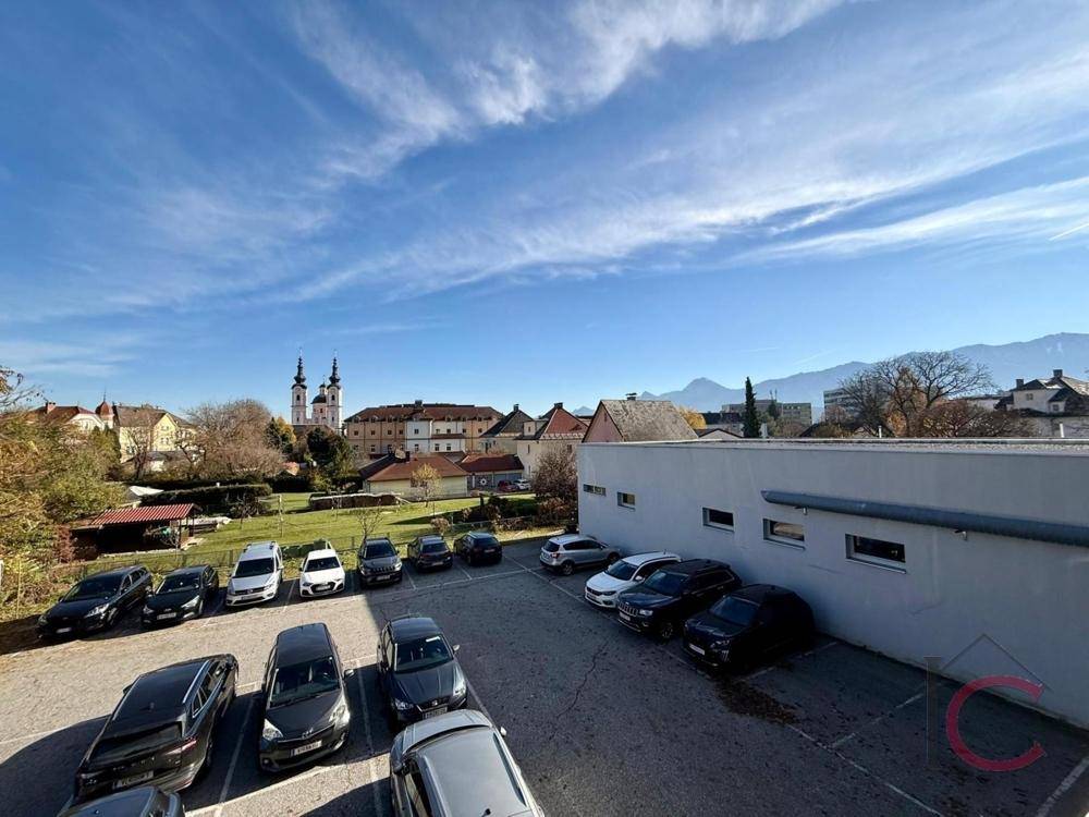 Außenparkplatz mit Blick auf die historische Kirche und die umliegenden Berge.