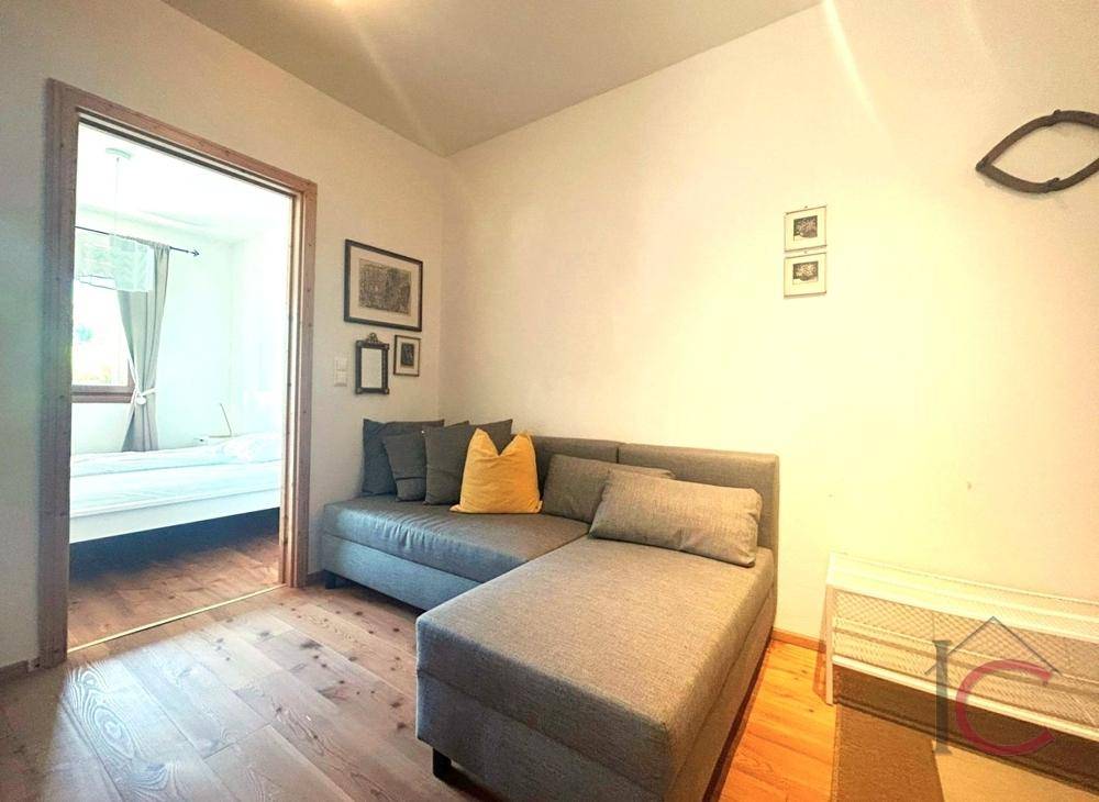 Gemütlicher Wohnbereich mit Sofa und Zugang zu einem weiteren Zimmer, ideal als Gästezimmer.