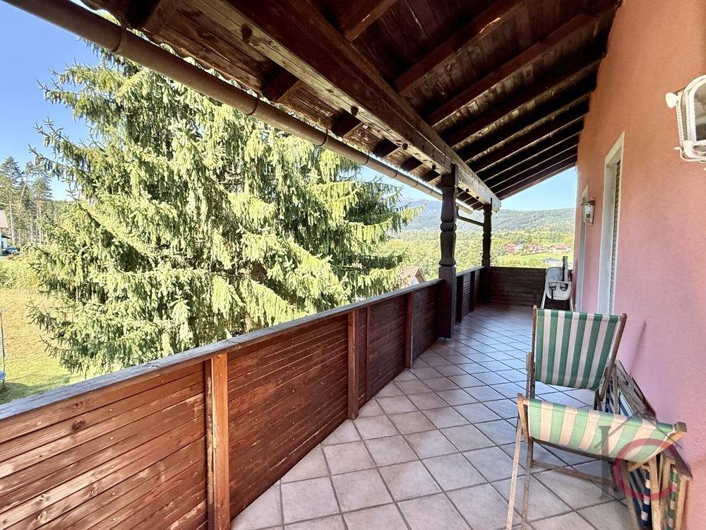 Langer Holzbalkon mit Fliesenboden und Blick auf die umliegende Natur.
