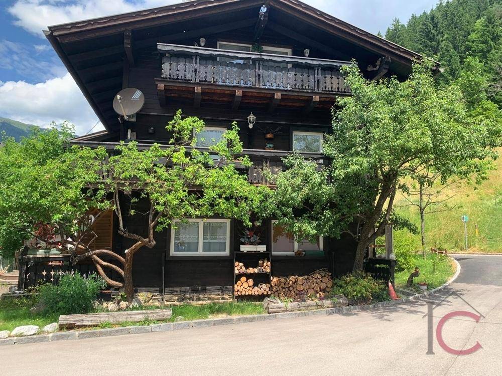 Traditionelles Holzhaus mit mehreren Balkonen und üppiger Vegetation in den Bergen.
