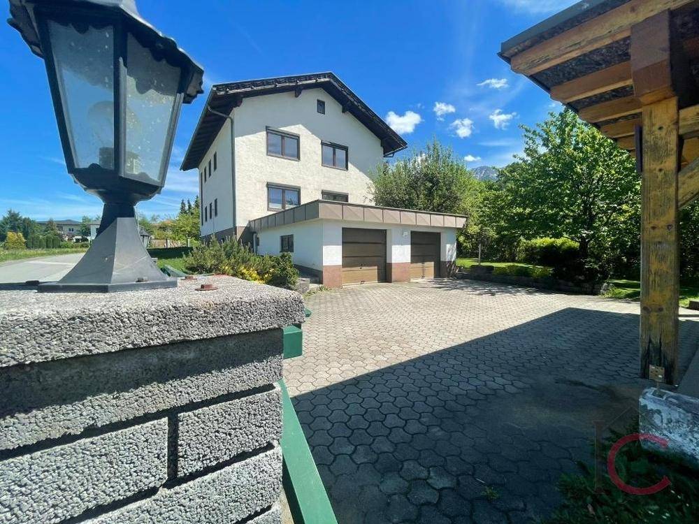 Wohnhaus mit Doppelgarage und gepflasterter Einfahrt, flankiert von einem dekorativen Laternenpfahl.