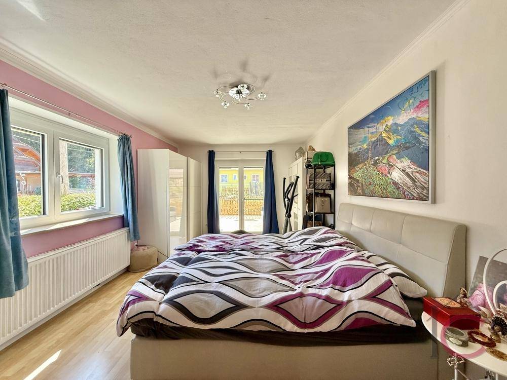 Geräumiges Schlafzimmer mit Doppelbett, Holzboden und direktem Zugang zu einem sonnigen Außenbereich.