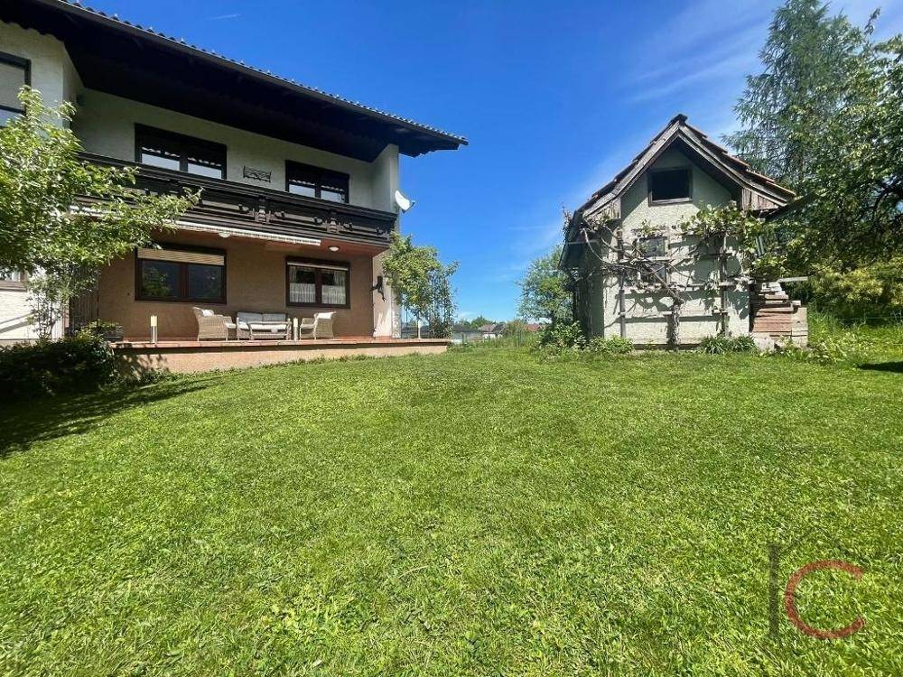 Großer grüner Garten hinter dem Haus mit Rasenfläche und einem kleinen Gartenhaus.