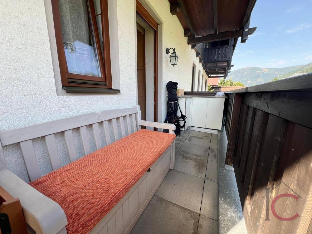 Schmaler Balkon mit Sitzbank und Blick auf die umliegende Berglandschaft und Natur.