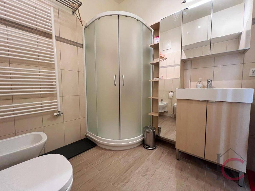 Funktionales Badezimmer mit Duschkabine, WC, Bidet und beheiztem Handtuchhalter.