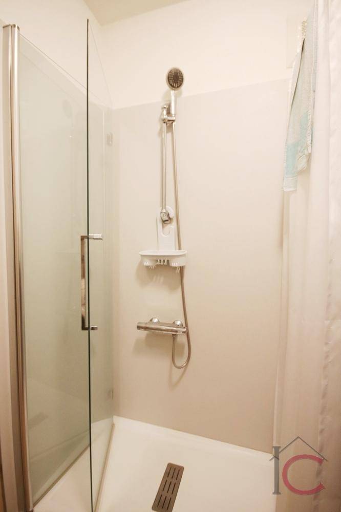 Moderne Duschkabine mit Glaswänden und Duschsystem in hellem Badezimmer.