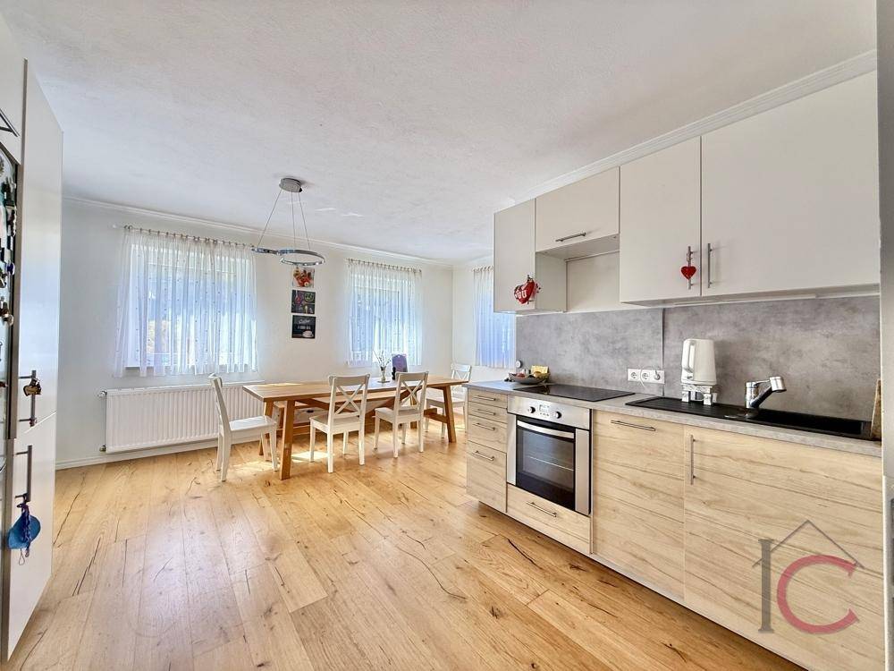 Helle Einbauküche mit modernen Schränken, Holzboden und integriertem Essbereich für Familienmahlzeiten.