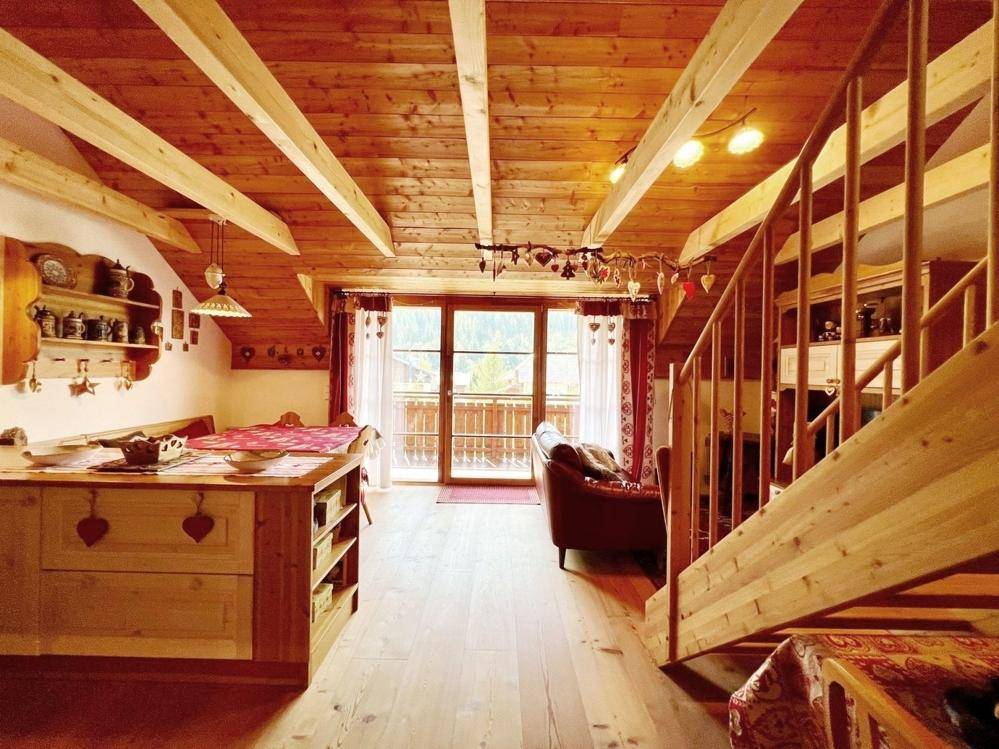 Offener Wohnbereich mit Holztreppe, Zugang zum Balkon und traditioneller Einrichtung.