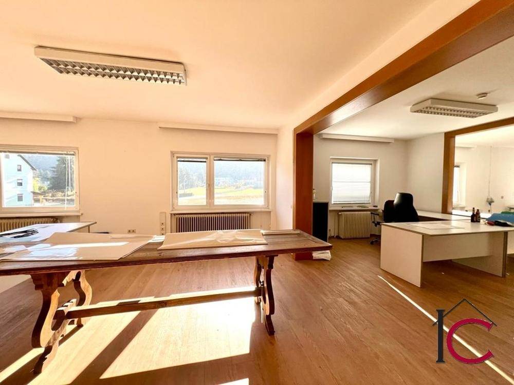 Großes Büro mit Holzboden, mehreren Fenstern und einem traditionellen Holztisch in der Mitte.