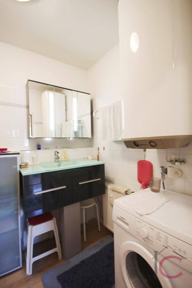 Funktionales Badezimmer mit Waschbecken, Spiegelschrank und Waschmaschine.