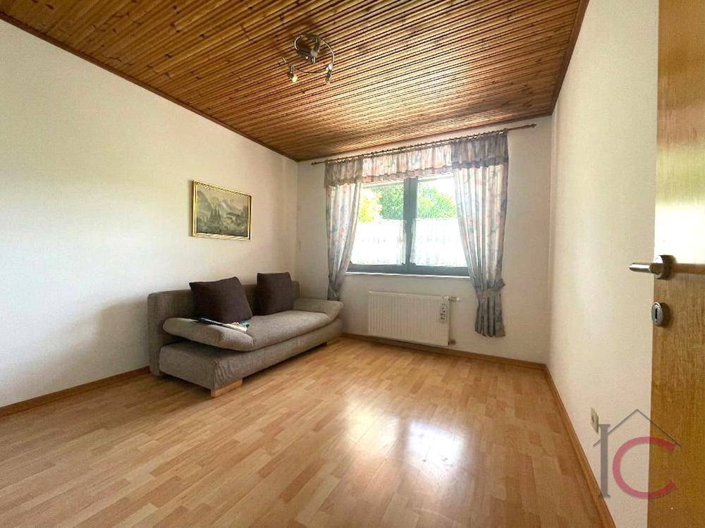 Helles Zimmer mit Sofa, Holzdecke und Laminatboden, ideal als Gäste- oder Arbeitszimmer.