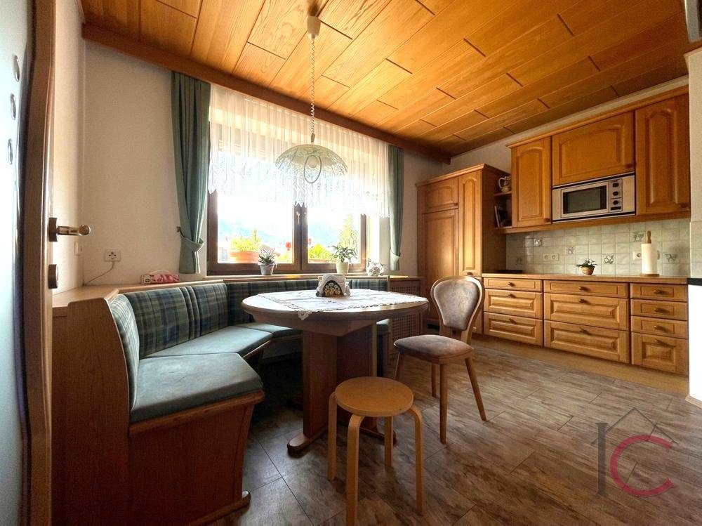 Gemütliche Küche im Landhausstil mit Holzeinbauten, Essbereich und Blick ins Grüne.