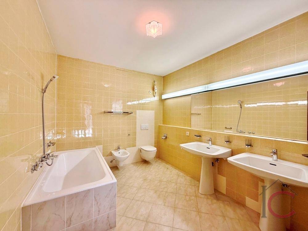Geräumiges Badezimmer mit gelben Fliesen, Badewanne, Bidet und Doppelwaschbecken.
