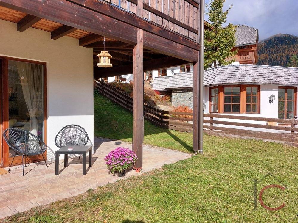 Erdgeschoss-Terrasse mit Sitzgelegenheiten und Zugang zum Gartenbereich des Hauses.